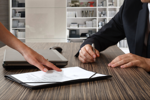 female hand pointing to businessman at signature place on a contract document